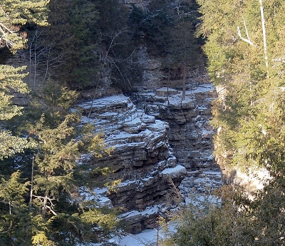 [Layers of snow-dusted rock with a handrail visible near the top.]